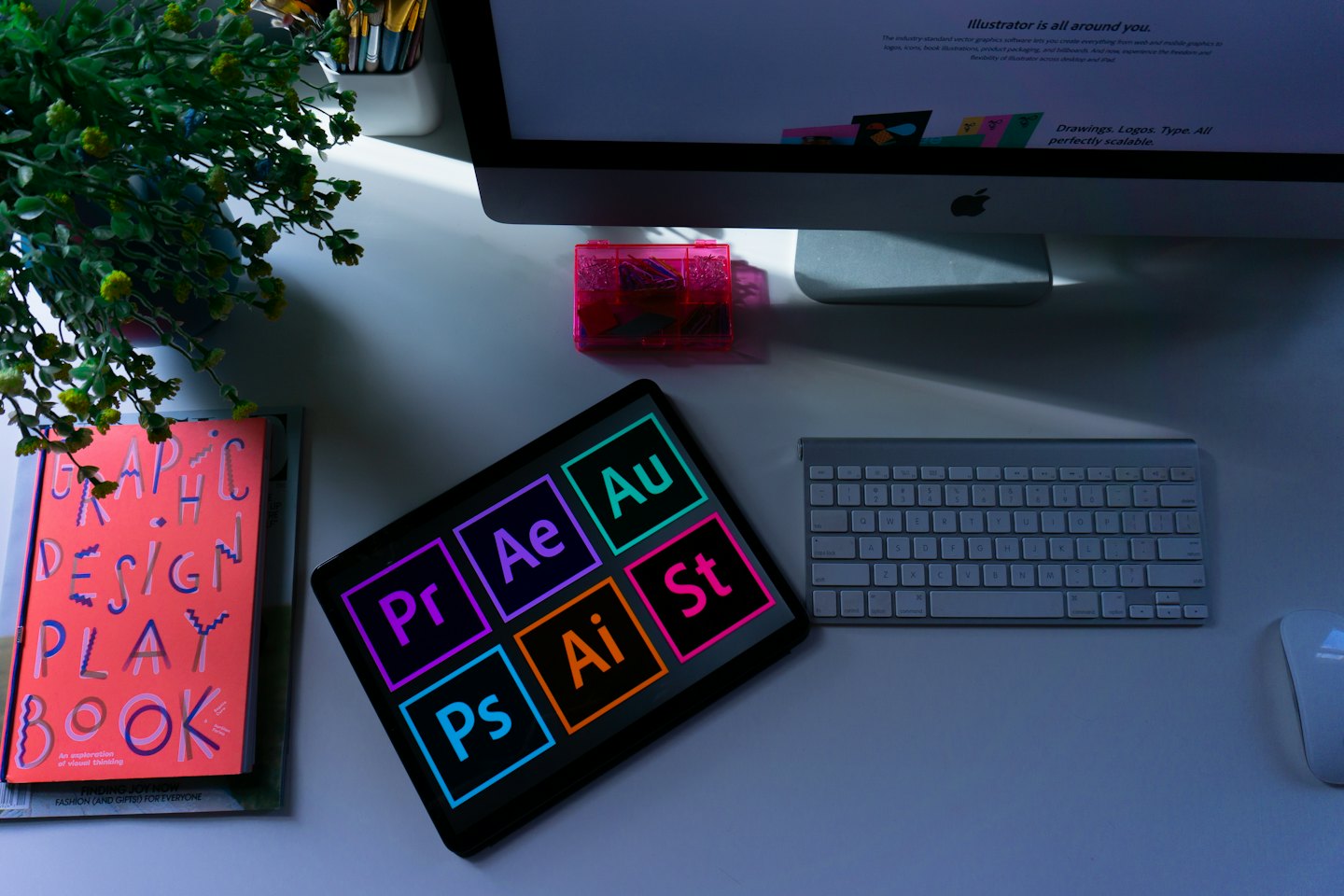 Scrivania organizzata di un graphic designer con computer, tablet e strumenti di progettazione.